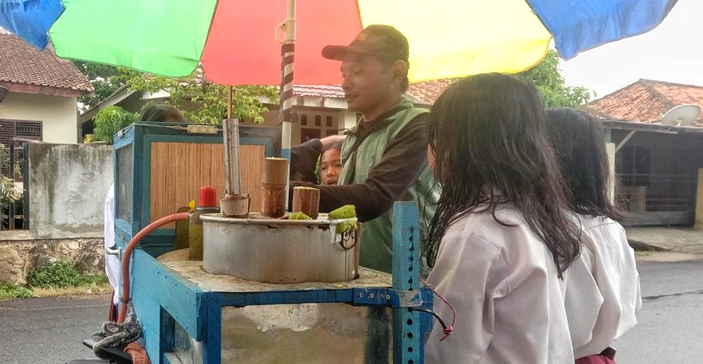 Pedagang Putu Mayam Gratis ke Pengendara saat Hujan